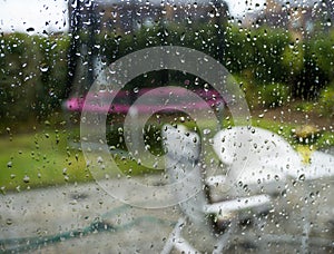 Autumn season looking through the window on a rainy day blurry garden background and rain drops on the glass window