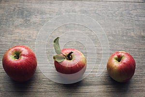 Autumn season still life with three apples over rustic wooden background. Copy space, horizontal.