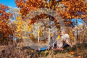 Autumn season walk. Senior couple hugging sitting in park. Man and woman relaxing outdoors