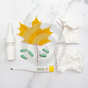 Autumn seasonal cold and illness. Tablets, nose spray and thermometer. Marble background. Top view. Flat lay. Care and