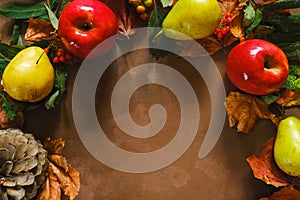 Autumn seasonal still life. Frame of fruits with autumn maple leaves on brown background.