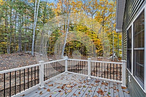 Autumn small deck view of a newly constructed house surrounded by trees and leaves