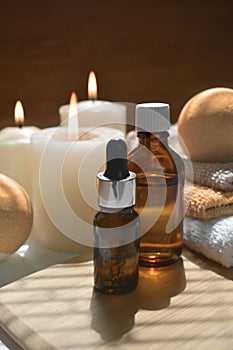 Autumn spa aromatherapy composition with essential oil bottles, bath bombs and lit candles on wooden background.