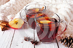 Autumn spiced tea with apples and pomegranates, side view against white wood background with cozy blanket