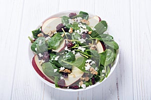 Autumn spinach salad with apple , cheese , walnut and dried cranberry . Healthy vegetarian food