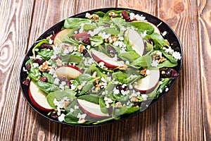 Autumn spinach salad with apple , cheese , walnut and dried cranberry . Healthy vegetarian food