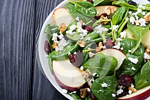 Autumn spinach salad with apple , cheese , walnut and dried cranberry . Healthy vegetarian food