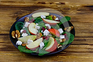 Autumn spinach salad with apple, feta cheese, walnut and dried cranberry on wooden table. Healthy vegetarian food