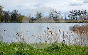 Autumn or spring landscape river, sky, clouds, grass and trees