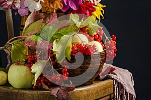 Autumn still life with apples, viburnum berries, autumn leaves on a vintage chair on a black background