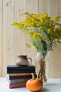 Autumn still life with books, pumpkins, cup, solidago bouquet