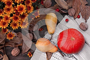 Autumn still life. Bouquet of orange chrysanthemums, pumpkin, pears and nuts on a wooden table. View from above. Thanksgiving,