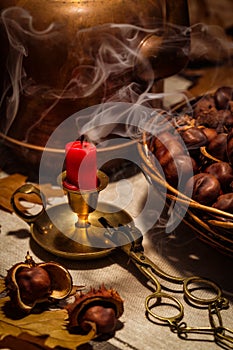 Autumn still life with a candle, chestnuts and an old copper coffeepot