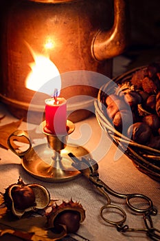 Autumn still life with a candle, chestnuts and an old copper coffeepot