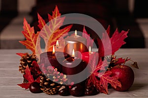 Autumn still life - candles, leaves and cones on the background of pillows