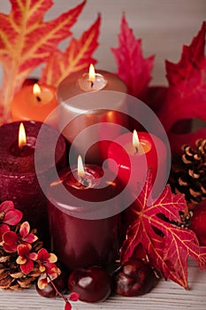 Autumn still life - candles, leaves and cones on the background of pillows