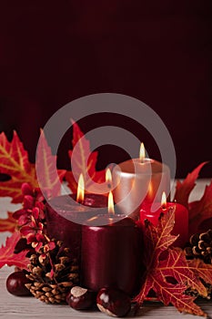 Autumn still life - candles, leaves and cones on the background of pillows