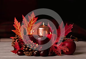 Autumn still life - candles, leaves and cones on the background of pillows