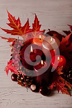 Autumn still life - candles, leaves and cones on the background of pillows