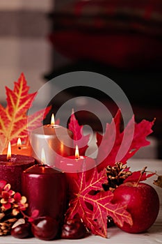 Autumn still life - candles, leaves and cones on the background of pillows