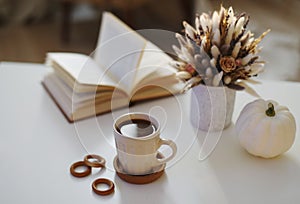 Autumn still life. Coffee cup, flowers, book and pumpkin. Hygge lifestyle, cozy autumn mood. Flat lay, Happy thanksgiving