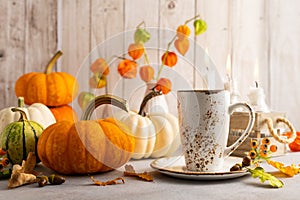 Autumn still life with cup of tea, pumpkins,flowers and candles on table.Thanksgiving day or halloween concept