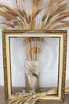 Autumn still life with ears of wheat and rye in a frame from a picture