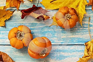 Autumn still life . Fallen maple leaves and orange pumpkins on a wooden blue background. Autumn harvest