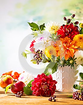Autumn still life with garden flowers. Beautiful autumnal bouquet in vase, apples and berries on wooden table. Colorful dahlia and