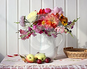 Autumn still life with garden flowers and fruit on a light background