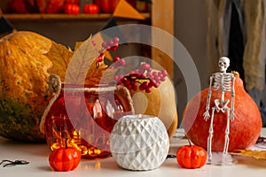 Autumn still life with pumpkin, candles, maple leaves and a skeleton