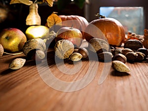 Autumn still life: pumpkins, apples, nuts and dry leaves on wooden background, fall harvest, selected focus.
