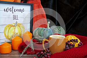 Autumn still life. Pumpkins, candles and a cup of juice on the table