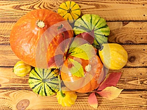 Autumn still life with pumpkins and fall leaves over wooden background. Top view