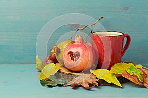 Autumn still life with red tea cup, pomegranate and leaves