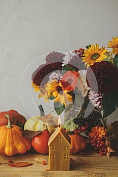 Autumn still life. Stylish pumpkins, autumn flowers, berries, leaves, candle on rustic wooden table. Happy Thanksgiving!