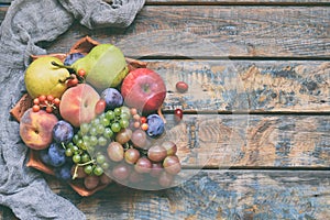 Autumn still life for thanksgiving with autumn fruits and berries on wooden background - grapes, apples, plums, viburnum, dogwood