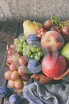 Autumn still life for thanksgiving with autumn fruits and berries on wooden background - grapes, apples, plums, viburnum, dogwood.