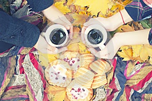 Autumn still life, two mugs with tea in hands, cakes, picnic in autumn park