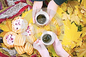 Autumn still life, two mugs with tea in hands, cakes, picnic in autumn park