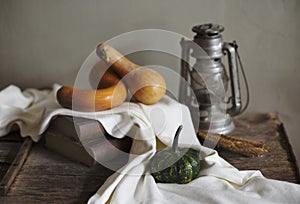Autumn still life with vintage lantern and pumpkin vegetable on rustic wooden table