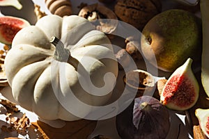 Autumn still-life with white pumpkin, sliced figs, walnuts and pears on wooden cutting board. Healthy eating concept.