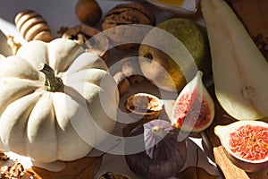 Autumn still-life with white pumpkin, sliced figs, walnuts and pears on wooden cutting board. Healthy eating concept.