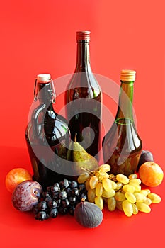 Autumn still life with wine bottles and fruits over red