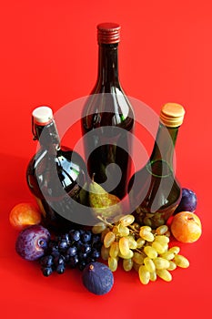 Autumn still life with wine bottles and fruits over red