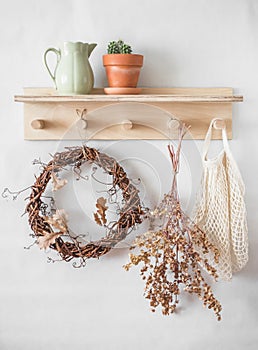 Autumn still life - wooden shelf with a vine wreath, ceramic jug, cactus, dried flowers, fabric bag in a bright room. Cozy eco