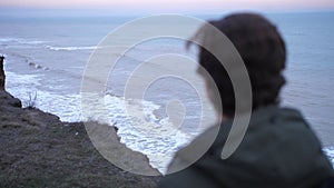 Autumn storm sea troubled water shoot, with young lone traveler hiking a cliff