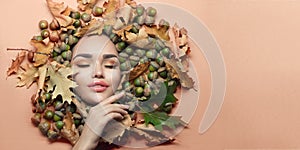 Autumn style Woman make-up. Beautiful fashion art model girl portrait with bright autumnal yellow, orange color leaves, oak acorns