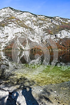 Autumn sunny morning on the Bohinj Lake with the reflection of the mountain