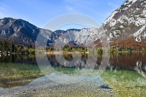 Autumn sunny morning on the Bohinj Lake with the reflection of the mountain